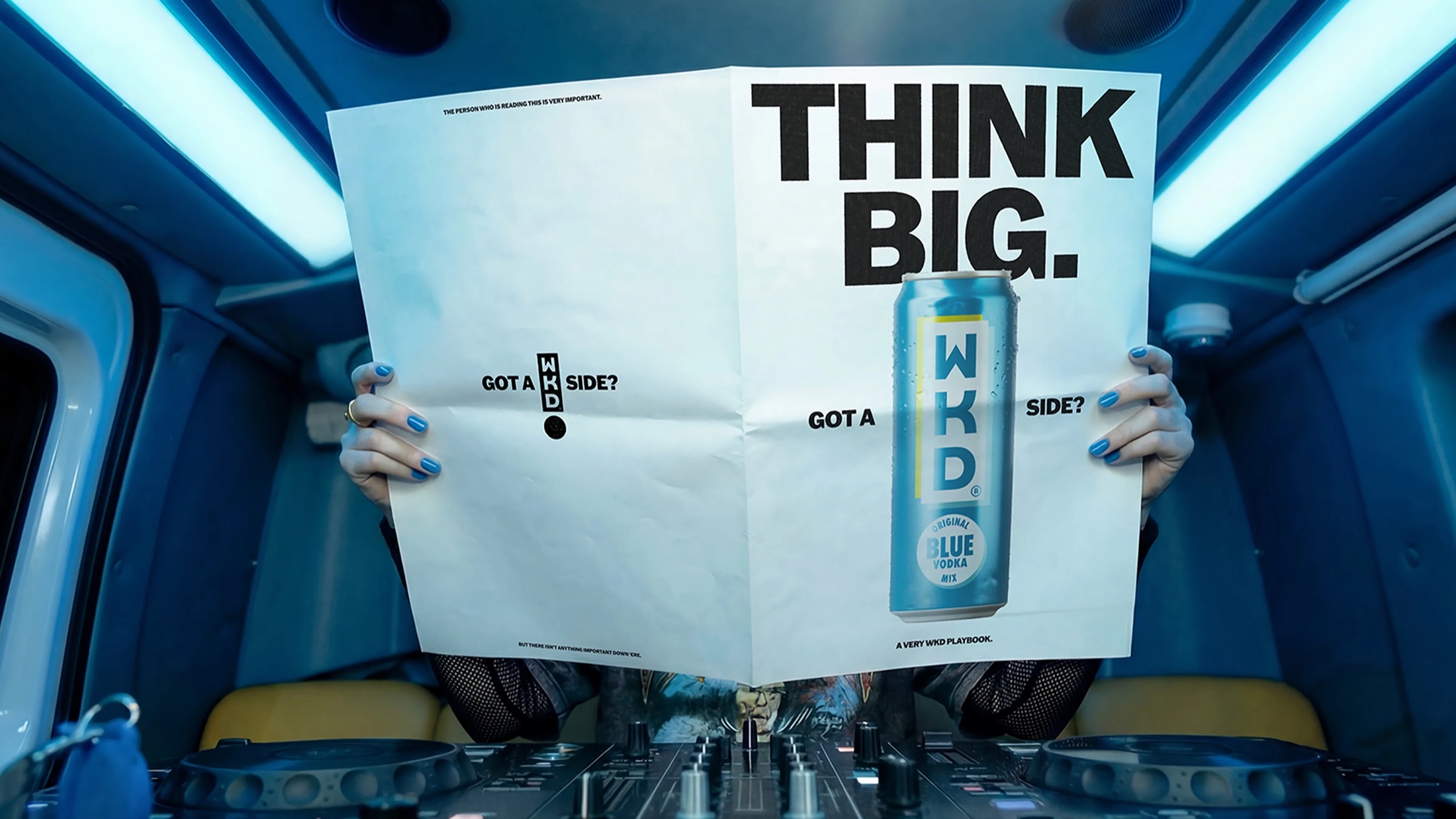 WKD Got a WKD Side campaign creative featuring a newspaper held inside a train